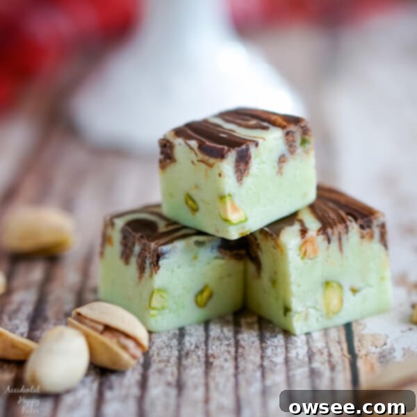A close up image of 3 pieces of Pistachio swirl fudge that show the chopped pistachios inside the creamy pastel green fudge.
