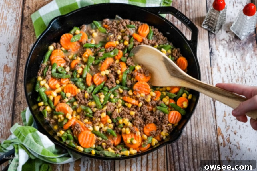 The mixed vegetables are added to the ground beef and sauce. 