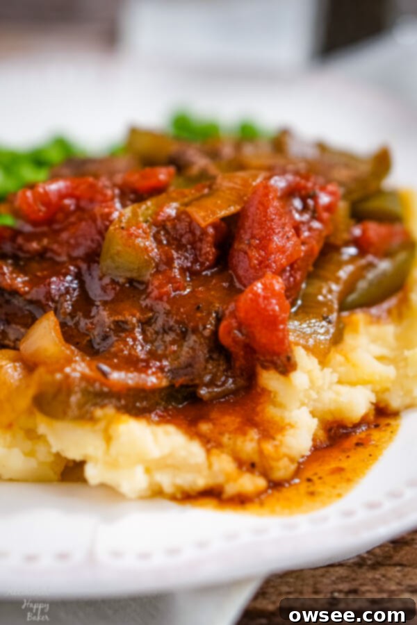 Tender Instant Pot BBQ Swiss Steak 8 BBQ Swiss Steak with peppers and onions is served up on a pile of cheddar mashed potatoes.