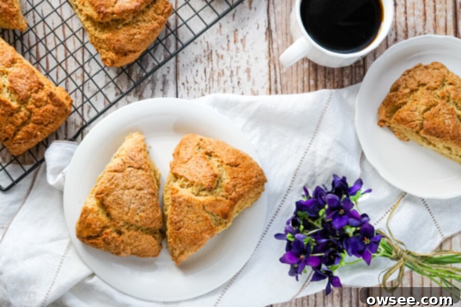 Bergamot-Kissed Scones 8 Two Earl Grey Scones on a plate sitting by a wire cooling rack full of fresh baked scones.