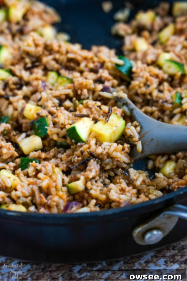 Sausage and wild rice filling cooking in a skillet, nearly ready to be stuffed into bell peppers.