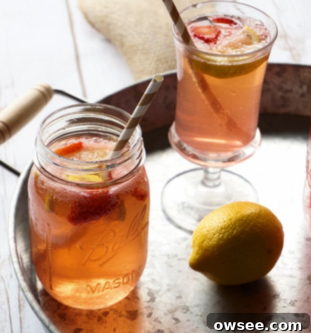 A glass of Strawberry Lemonade Shandy with a sliced strawberry garnish.