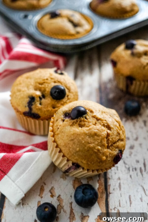 Wholesome Blueberry Bran Muffins 8 Two blueberry bran muffins on a red and white striped towel, highlighting their homemade charm and inviting texture.