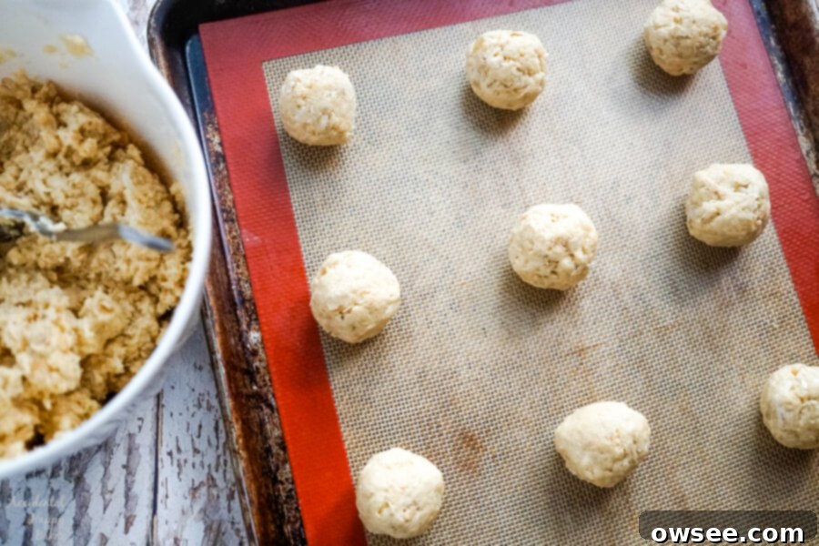 A pristine sheet pan filled with perfectly uniform cookie dough balls, carefully rolled to approximately 1.5 inches and evenly spaced, patiently awaiting their transformation in the oven.