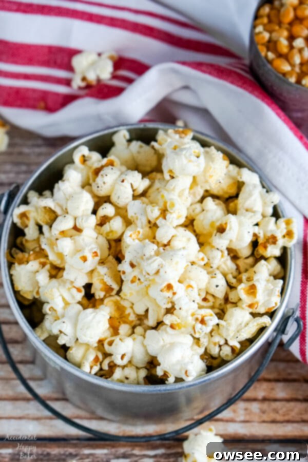 A cozy serving bowl filled with freshly made popcorn, accompanied by a festive red and white striped kitchen towel, ready for snacking.