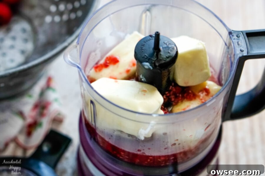 The cooled raspberry honey mixture and softened butter are combined in a food processor, ready to be blended into a creamy spread.