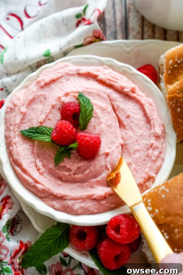 Honey-Kissed Raspberry Butter 8 A bowl of vibrant pink homemade raspberry honey butter with a butter knife, ready to be spread on your favorite treats.