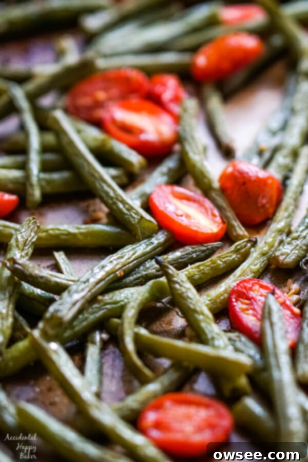 Vibrant Roasted Green Beans and Tomatoes 7 A close up image of a spatula scooping up a serving of roasted green beans and tomatoes.