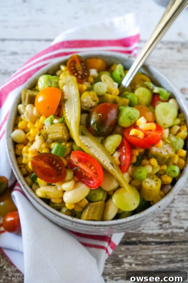 Vibrant Succotash Medley 2 A vibrant bowl of succotash salad, rich with corn, lima beans, tomatoes, and scallions, garnished with pickled okra slices.
