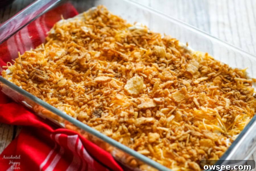 A baking pan filled with French Onion Smothered Pork Chops, layered with sour cream dip, cheddar cheese, and crispy fried onions, ready for the oven.