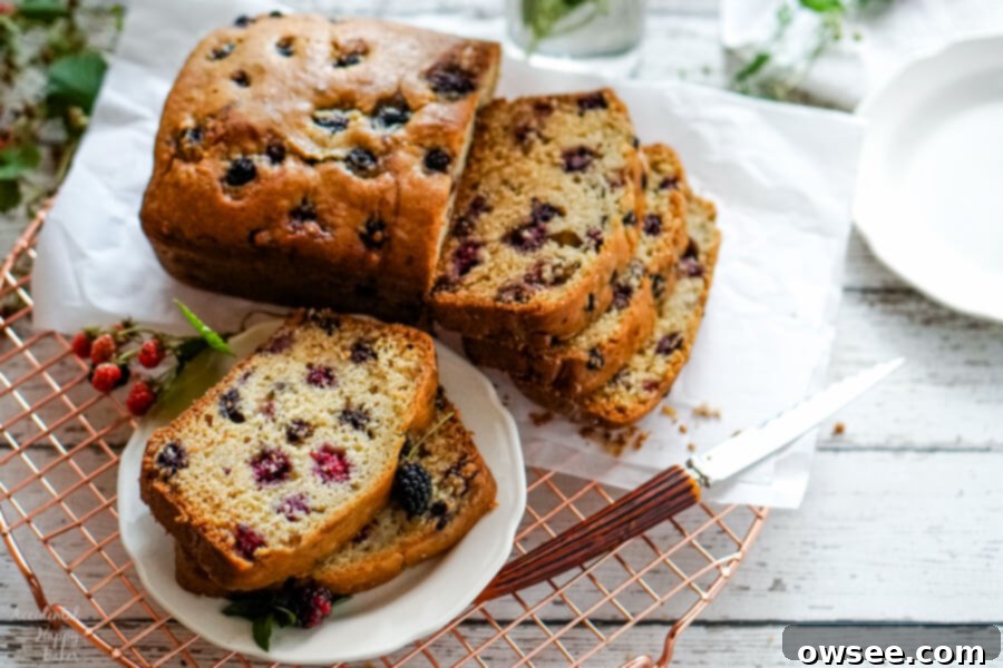 Homemade Blackberry Bread 6 Two slices of blackberry bread on a white plate next to a loaf of sliced blackberry bread.