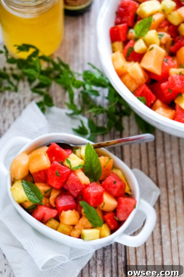 Sweet Watermelon Delight 6 A small white bowl containing a serving of watermelon fruit salad, garnished with fresh mint sprigs on the side, ready to be enjoyed.