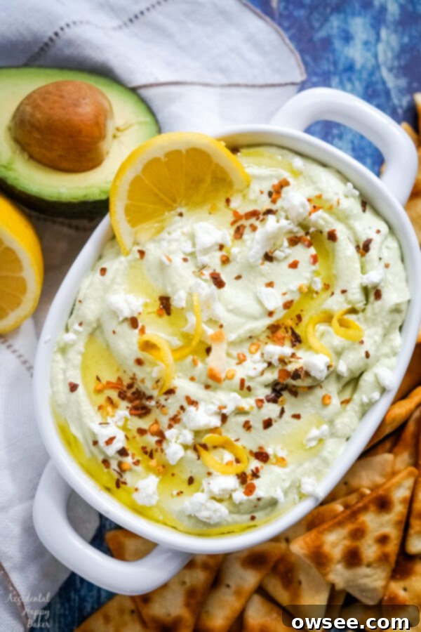 Zesty Feta Spread 2 A white bowl full of lemon feta dip surrounded by pita chips and garnished with sliced lemons.
