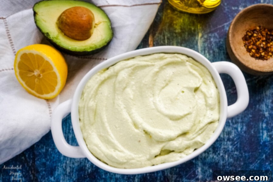 A bowl of lemon feta dip sitting next to half an avocado and lemon. 
