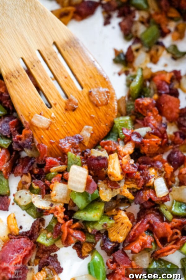 Diced onions, green bell peppers, and sliced mushrooms are being cooked in a large skillet with rendered bacon grease, creating an aromatic base.