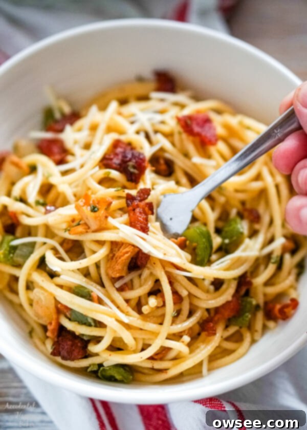 A fork twirls a generous portion of freshly made spaghetti carbonara in a deep white bowl, showing the creamy sauce and bits of bacon and vegetables.