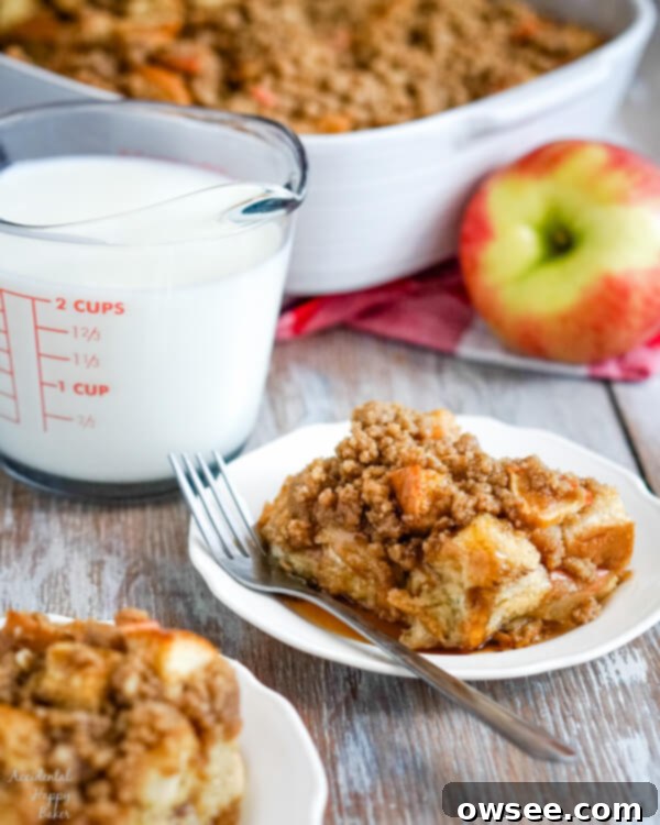 Two servings of Cinnamon Apple French Toast Casserole on white plates with a measuring cup of milk to the side, ready to be enjoyed.