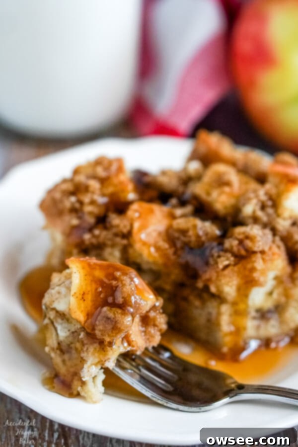A close-up image of a delicious bite of French toast casserole, glistening with maple syrup, showcasing the moist bread and apple chunks.