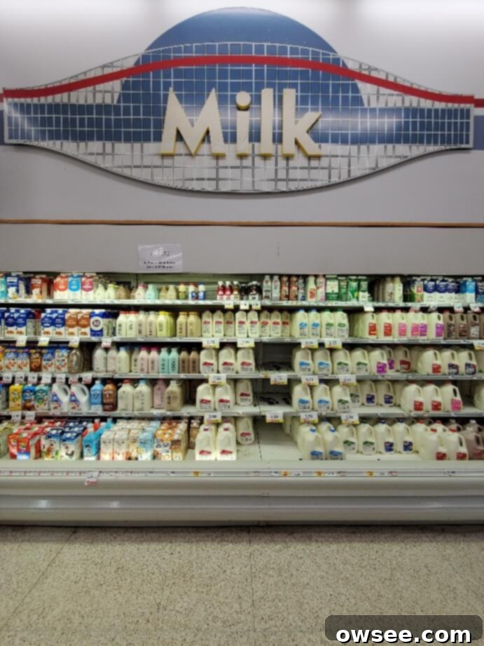 A vibrant display of fresh milk cartons in various types and sizes, neatly arranged in a refrigerated section of a Hy-Vee food store.