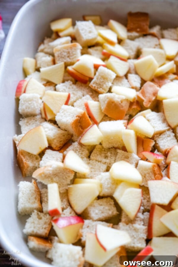 Bread cubes and chopped apples are carefully layered in a 9x13 inch baking pan, forming the delicious foundation of the casserole.