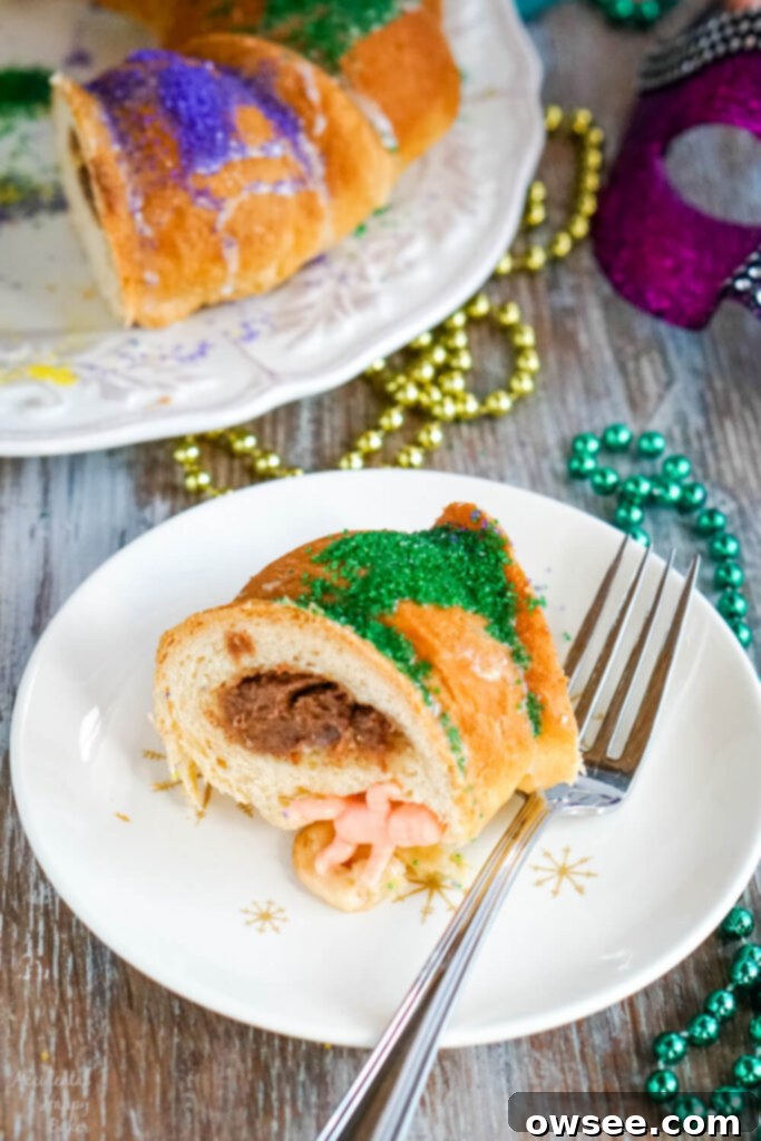 Effortless King Cake Celebration 3 A slice of king cake on a white plate with mardi gras beads in the background.