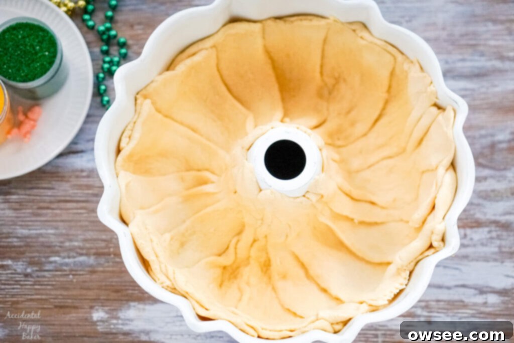 Effortless King Cake Celebration 4 Crescent rolls are pressed into a bundt pan.