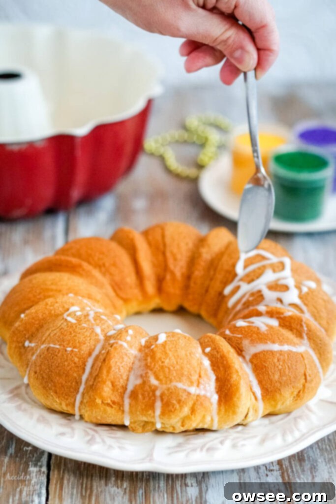 Effortless King Cake Celebration 8 The baked king cake is drizzled with glazed before being decorated with colored sugar.