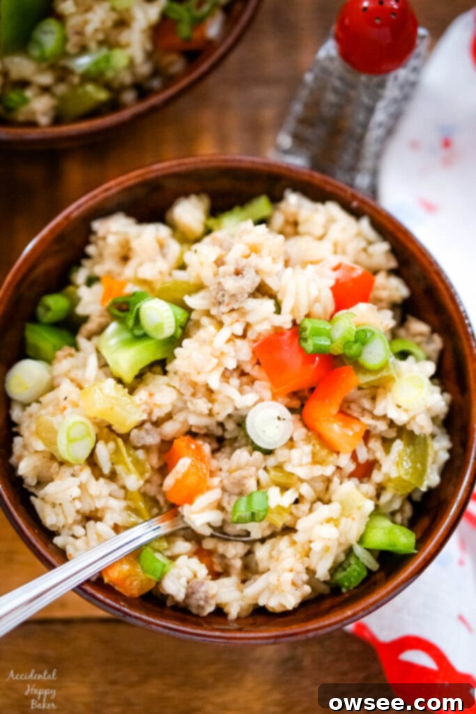 Savory Sausage Dirty Rice 2 A brown bowl full of dirty rice with sausage on a wooden tray.