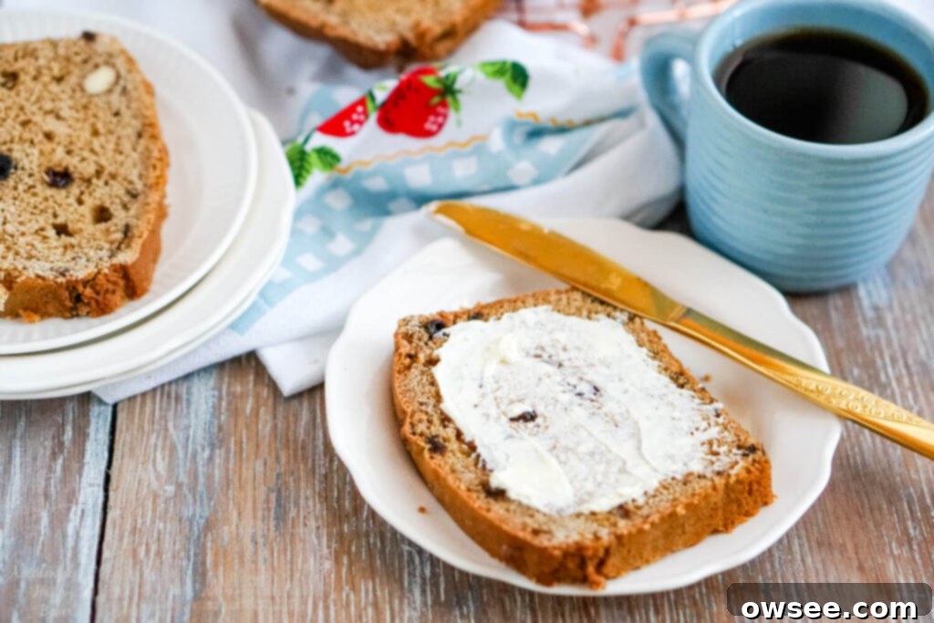 Bara Brith Traditional Welsh Tea Bread 3 A thick slice of tea loaf slathered with butter next to a cup of tea.
