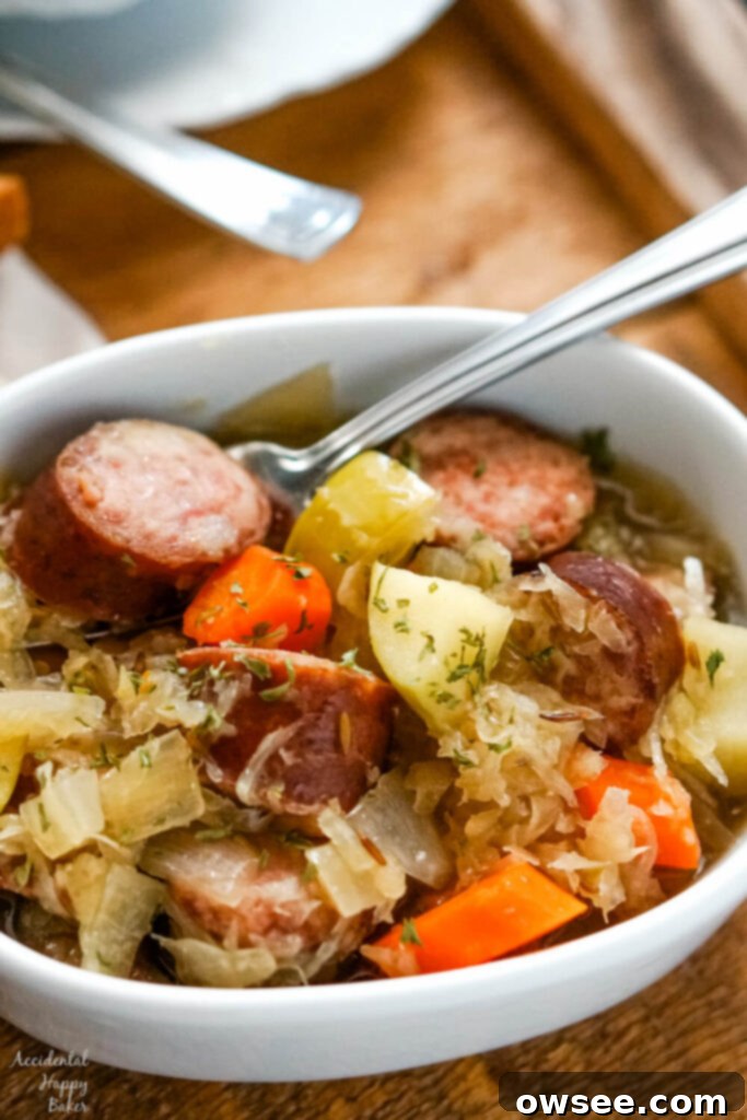 Hearty Slow Cooker Kielbasa and Sauerkraut Dinner 2 A white bowl of slow cooker kielbasa and sauerkraut on a wooden tray.