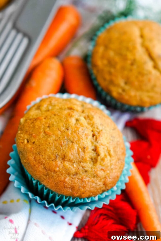 Wholesome Banana Carrot Muffins 3 A single banana carrot muffin nestled in a cupcake liner, with fresh carrots delicately placed beside it, highlighting the ingredients.