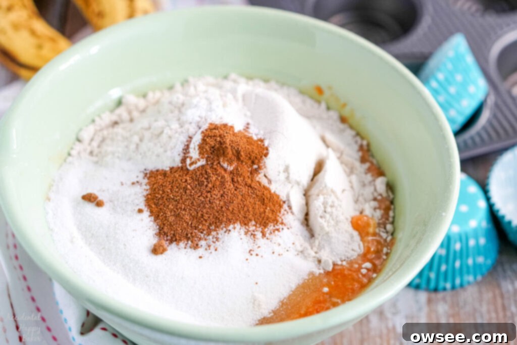 Wholesome Banana Carrot Muffins 6 Dry ingredients like flour, baking soda, and spices carefully layered on top of the wet mixture in a mixing bowl.