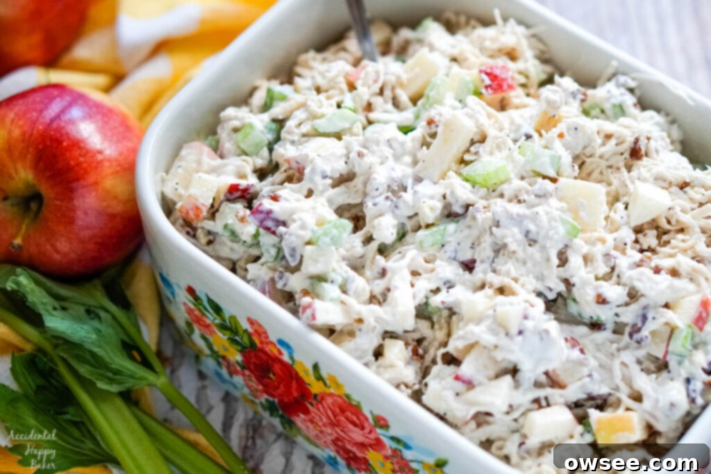 A vibrant bowl of apple pecan chicken salad garnished with fresh herbs and served in a beautiful floral bowl, ready to be enjoyed.