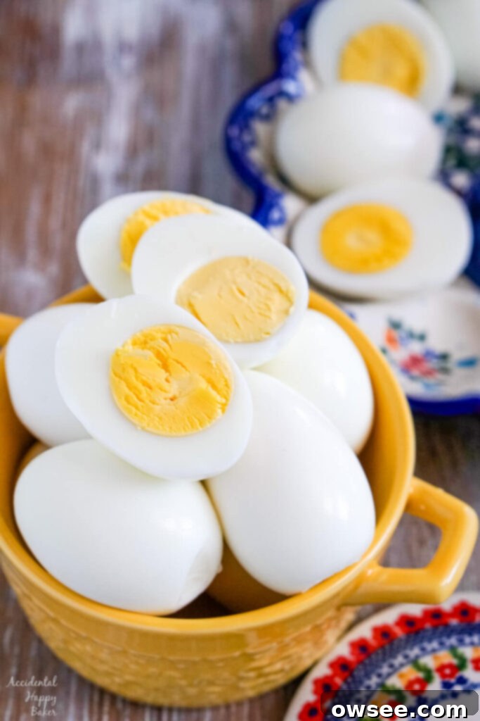 Achieve Perfect Hard Boiled Eggs Every Time 2 A yellow bowl full of hard boiled eggs, with a few sliced hard boiled eggs laying on top.