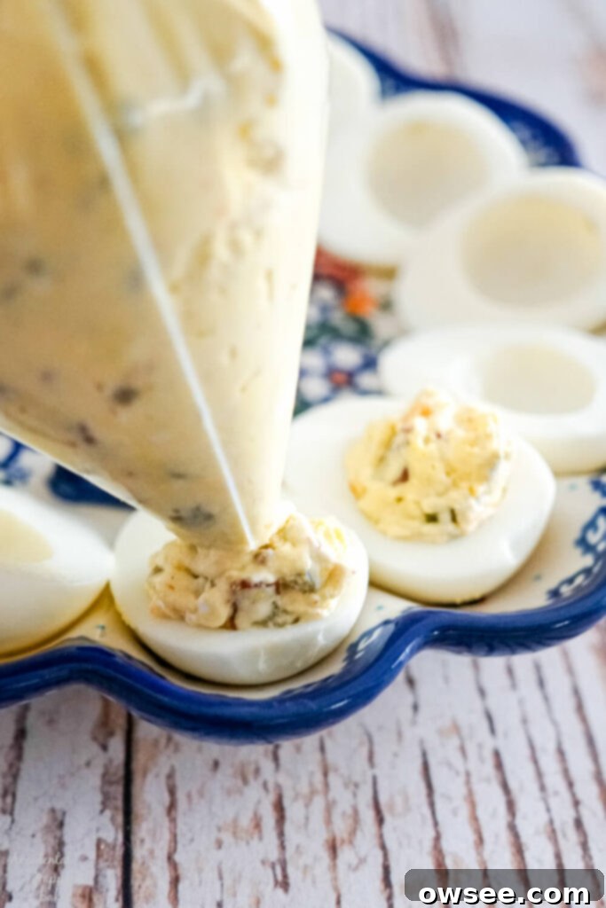 The end of the baggie is cut off and the filling is piped into the sliced egg halves. 
