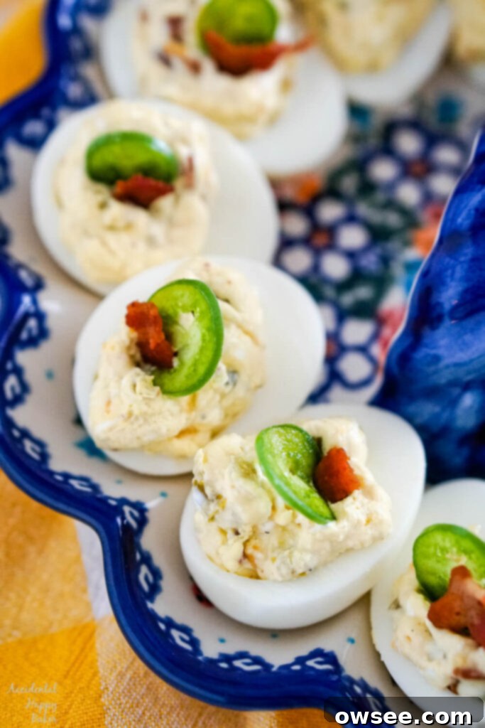 Deviled eggs with a slice of jalapeno and a bit of bacon displayed on a egg plate.