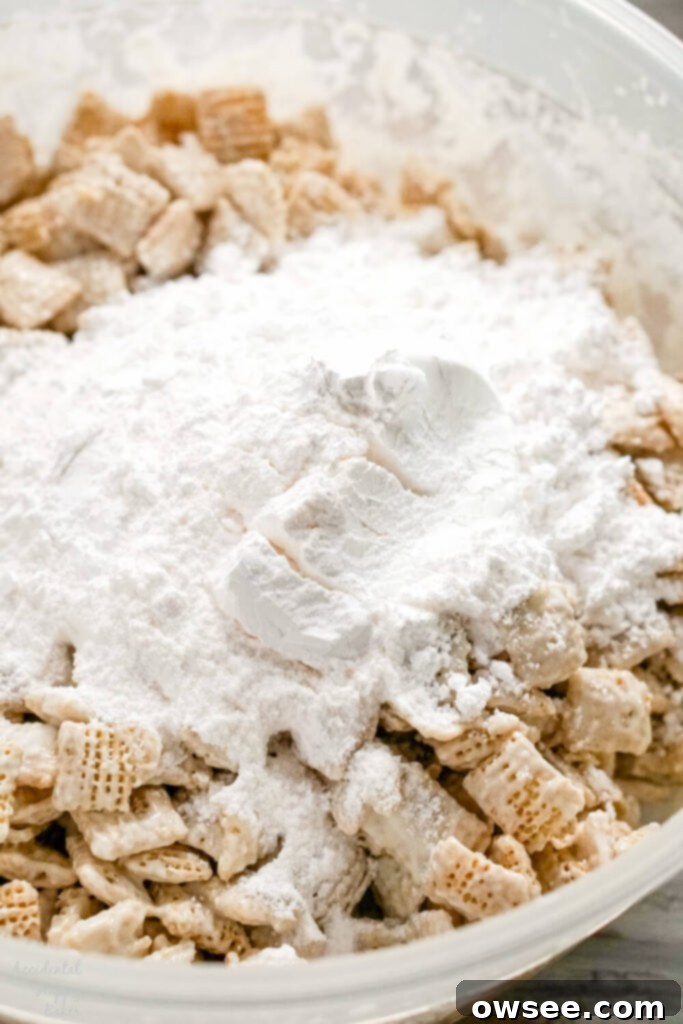 Ultimate Banana Cream Pie Muddy Buddies 6 Almond bark covered cereal with powdered sugar and banana pudding mix in a bowl.