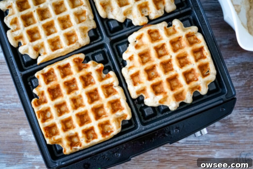 Homestyle Oatmeal Waffles 8 A freshly cooked oatmeal waffle being carefully removed from the waffle maker with a fork.