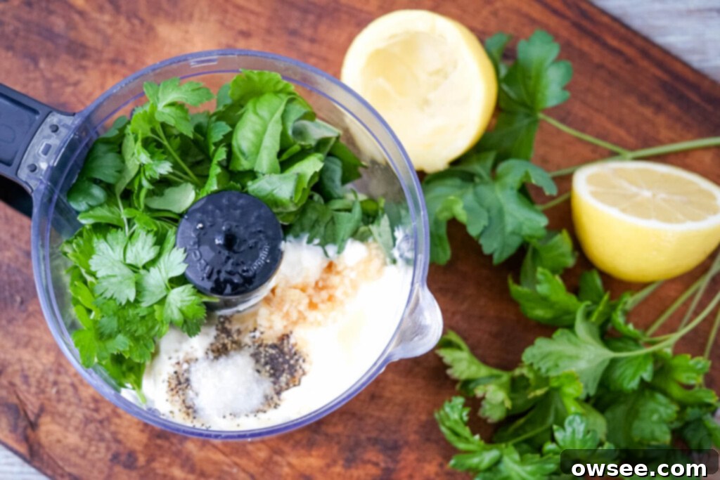 Creamy Mediterranean Tuna Salad 3 A food processor with the ingredients for the creamy herbed lemon dressing, including mayo, fresh herbs, and lemon.