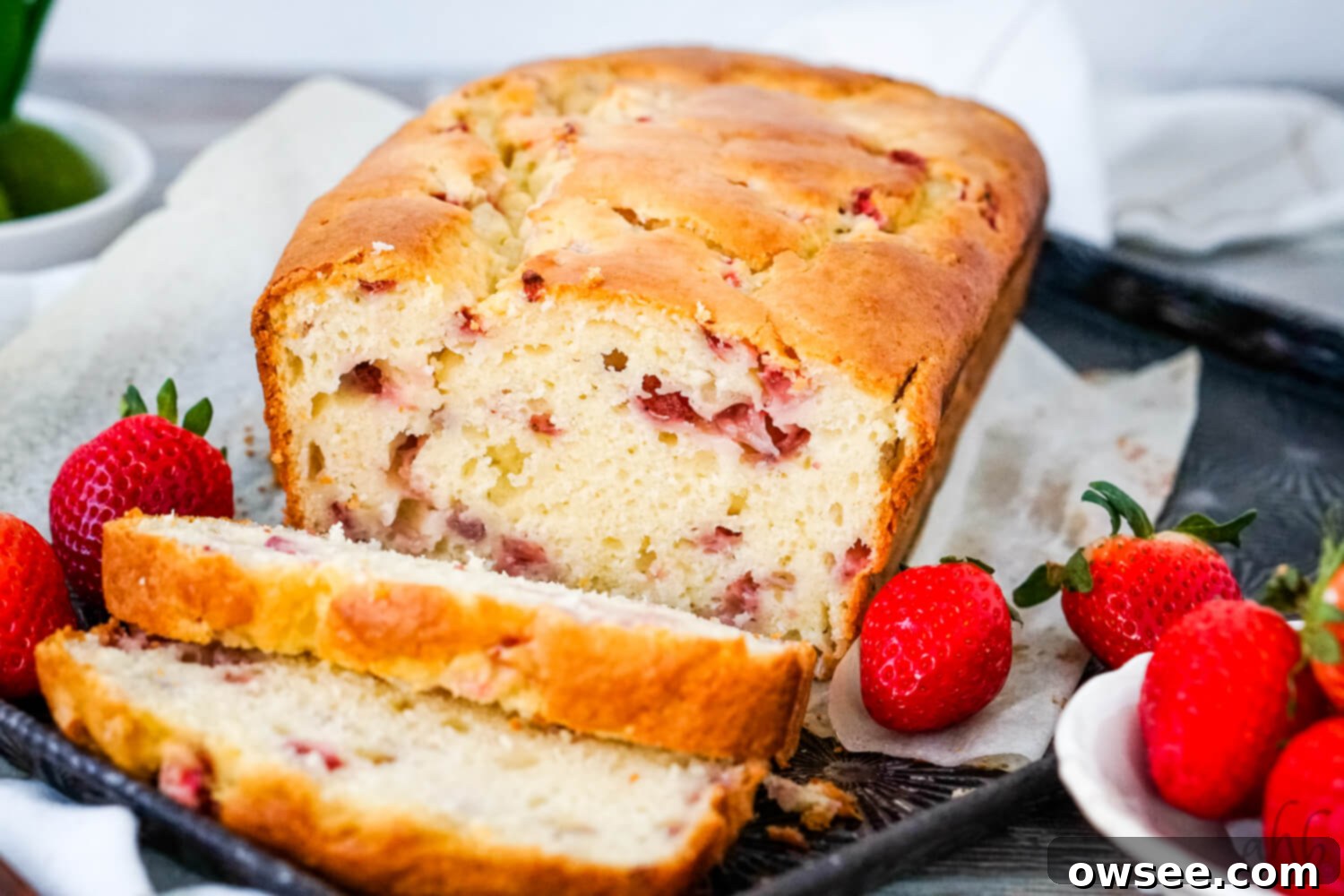 Simple Strawberry Yogurt Loaf 2 A sliced loaf of Strawberry Bread on a tray with fresh strawberries on each side.