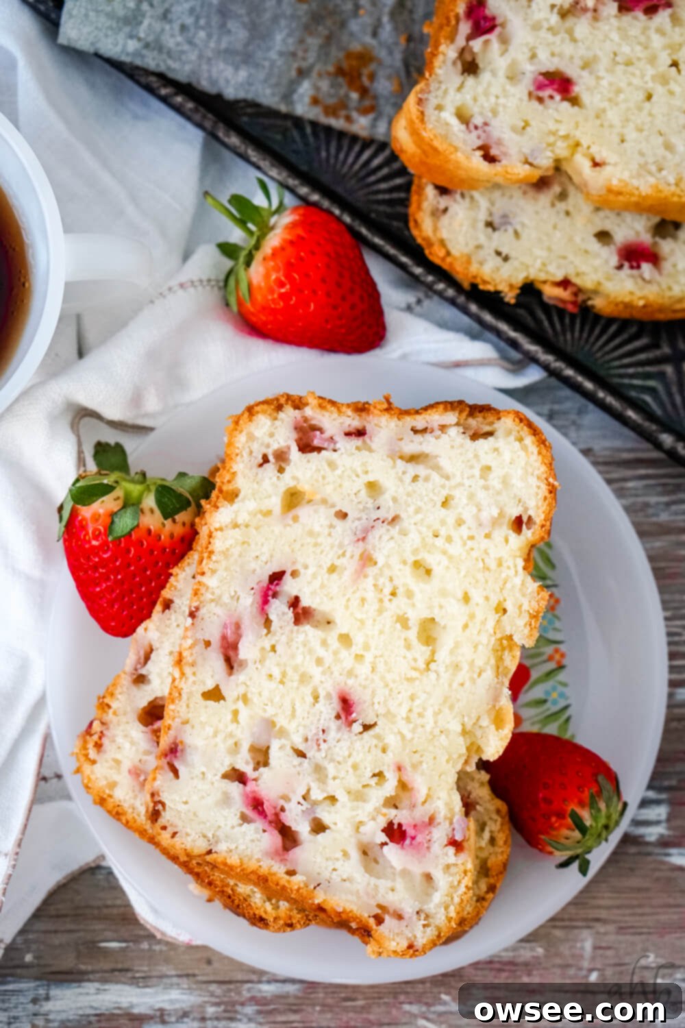 Simple Strawberry Yogurt Loaf 3 Two Slices of Strawberry Bread on a white plate surrounded by fresh strawberries.