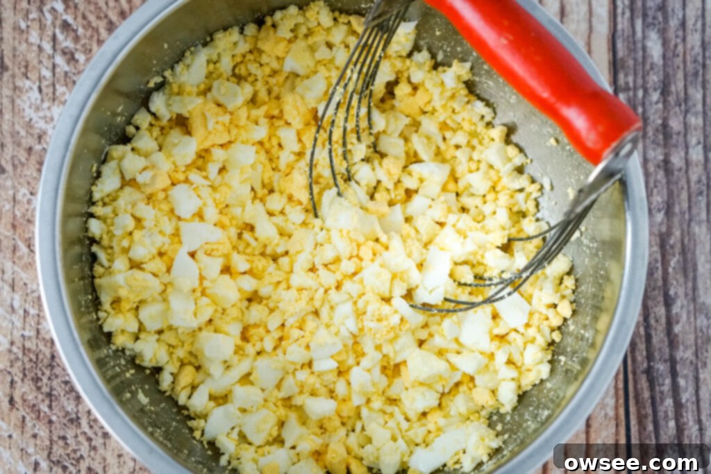 a bowl of chopped hard boiled eggs with a pastry blender to one side. 