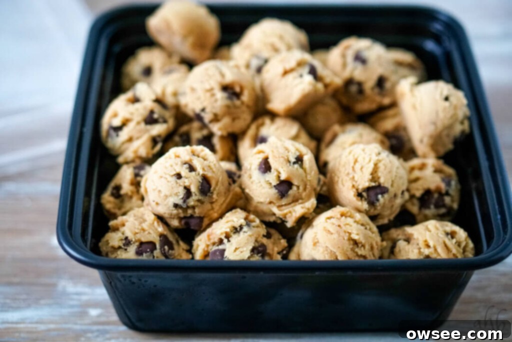 A freezer-safe container filled with neatly scooped, frozen chocolate chip cookie dough balls, ready to be labeled and stored in the freezer.