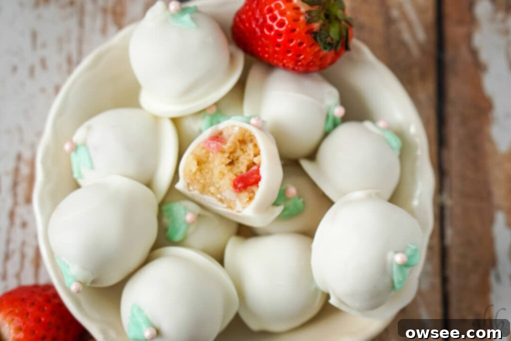 Easy Strawberry Cheesecake Truffles 9 A serving platter filled with finished strawberry cheesecake truffles, some garnished with strawberry slices.