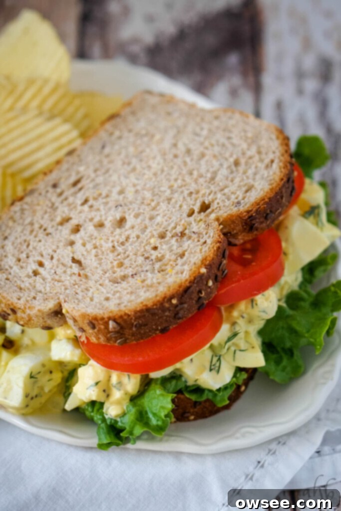 Kickin' Buffalo Tuna 4 A homestyle egg salad sandwich with lettuce and tomato on a white plate.