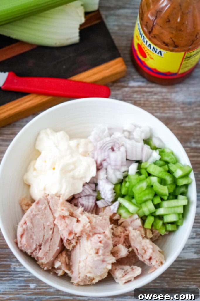 Kickin' Buffalo Tuna 5 Ingredients for buffalo tuna salad laid out on a white surface.