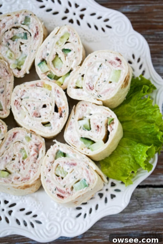 Tuna Roll-Ups 3 A plate of white tuna pinwheels served on a bed of fresh lettuce, elegantly presented on a decorative white plate.