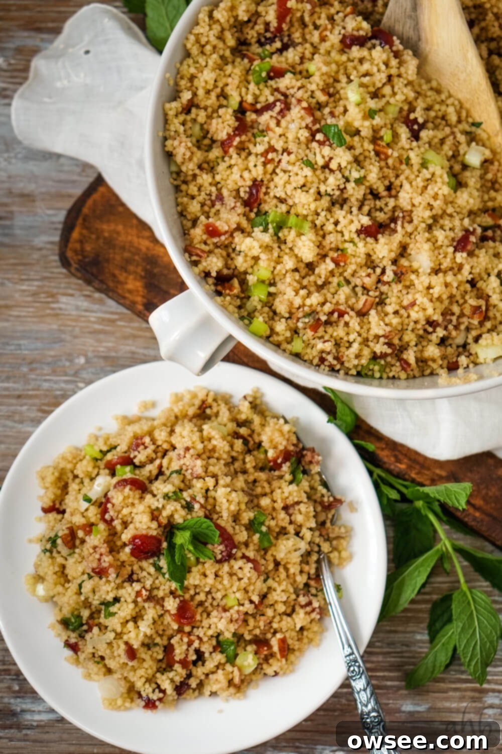 Vibrant Cranberry Couscous Salad 10 A beautiful presentation of Cranberry Couscous Salad, with a single serving on a white plate next to a large white serving bowl, both filled with the vibrant salad.